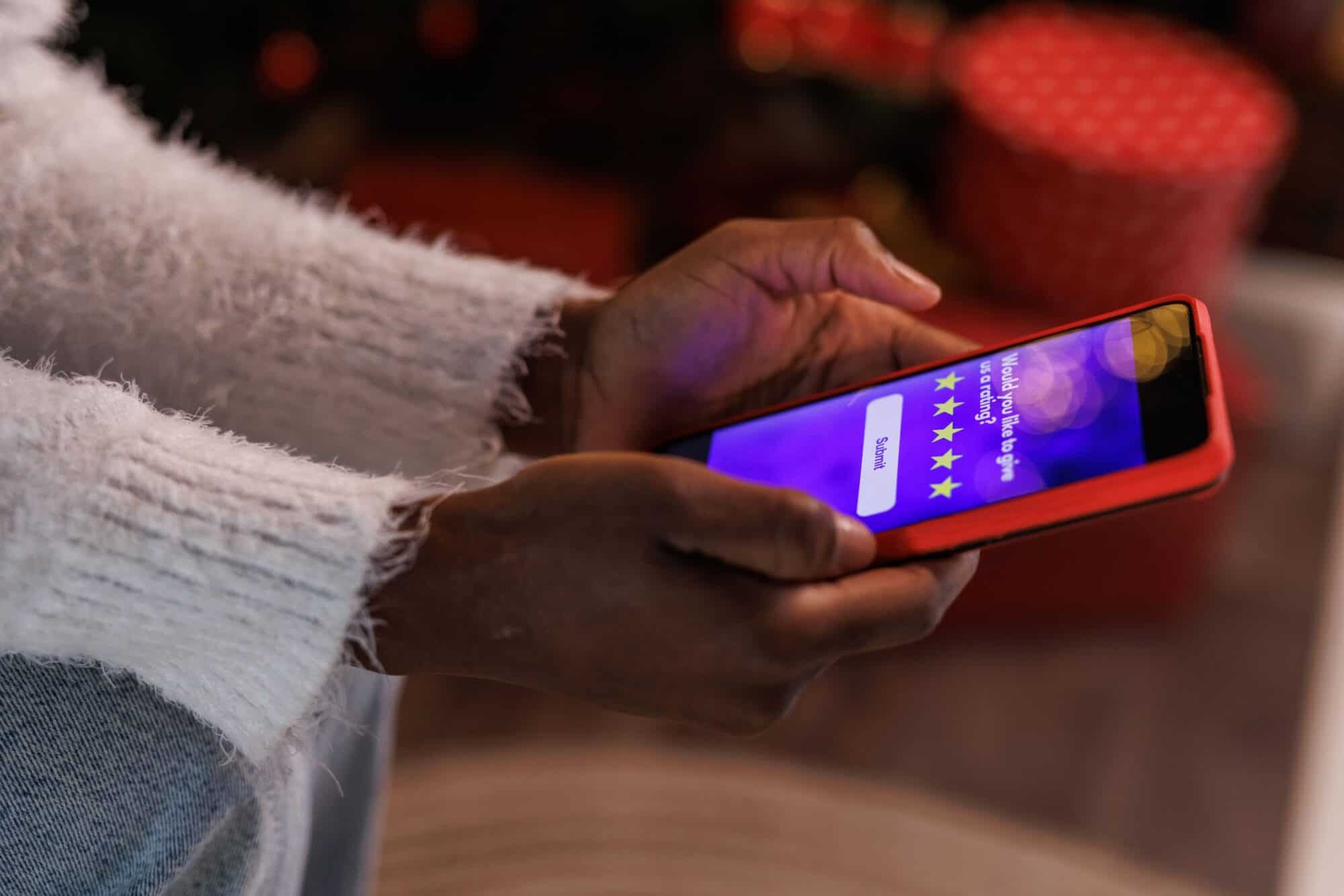 A woman looks at a 5-star review on her phone.
