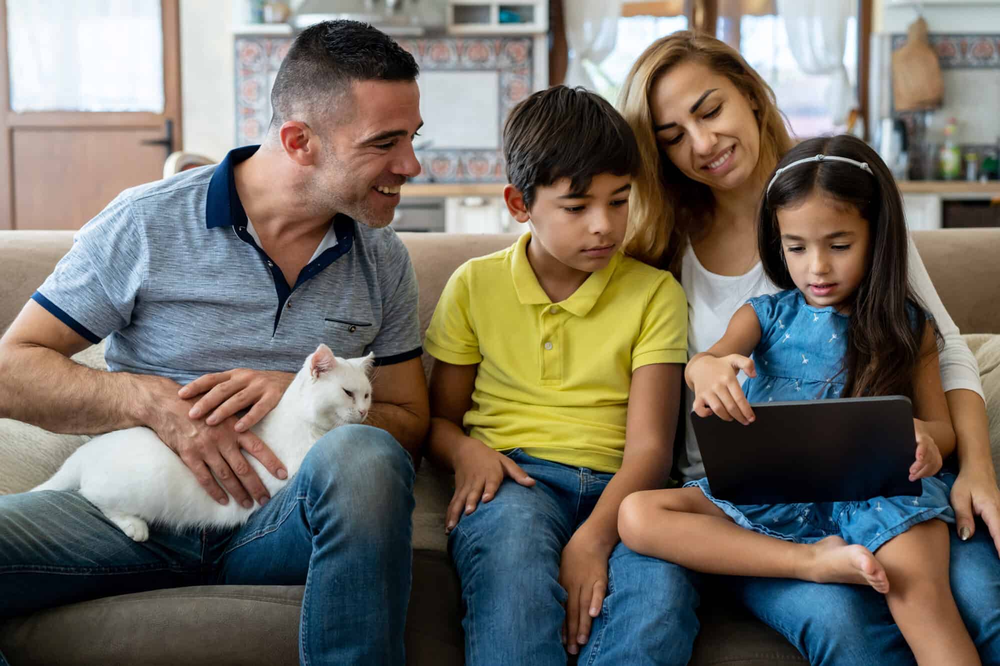 A family looks at a tablet with their cat.