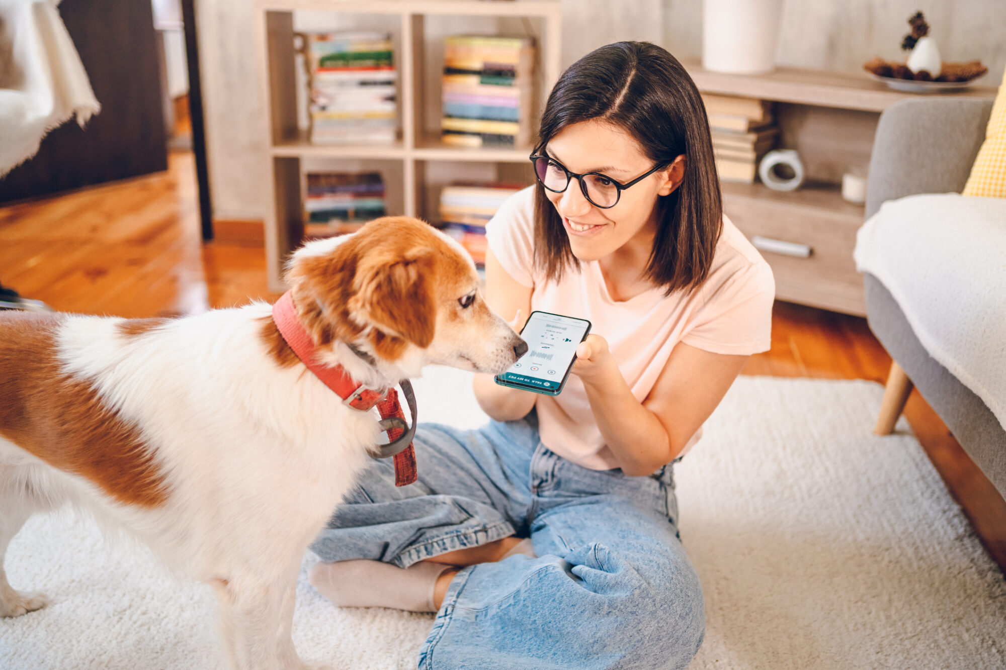 A woman using voice search on her phone with her dog nearby.